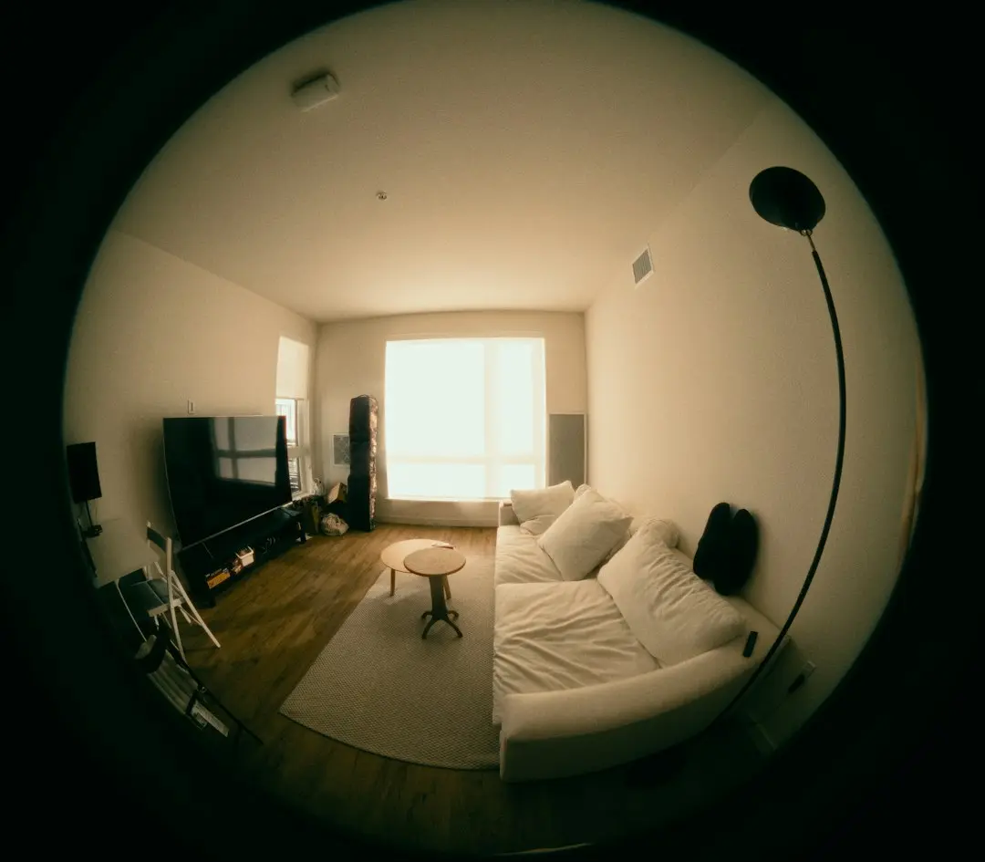 A wide-angle view of a calm living room with a TV, a white sofa and a floor lamp, where GaroxTV streams over the internet